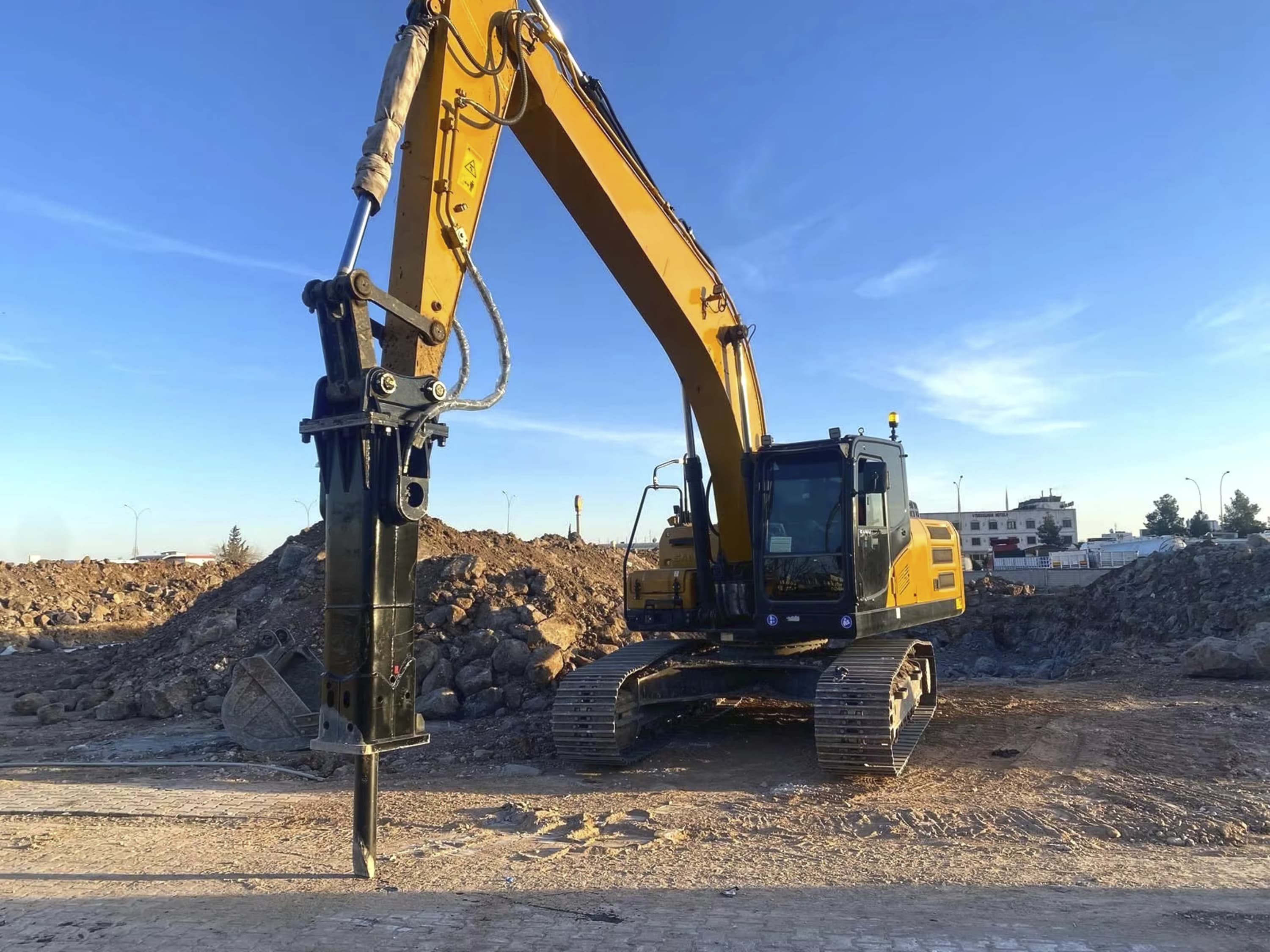 An excavator-mounted breaker on a construction site, from the DemaRock E Series brochure